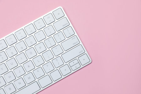 Modern white wireless keyboard on pink background, top view. Space for text