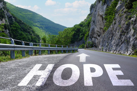 Hope word and arrow on asphalt road in mountains