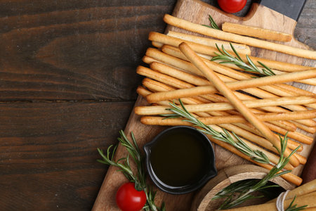 Delicious grissini sticks served on wooden table, flat lay. Space for text