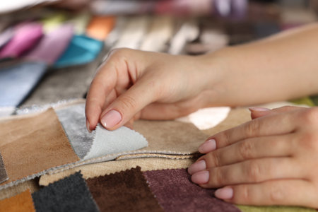 Woman choosing fabric among different samples indoors, closeup