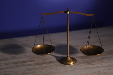 Scales of justice on wooden table against dark backgroundの写真素材