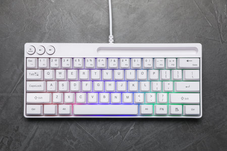 Modern white keyboard with RGB lighting on grey table, top view