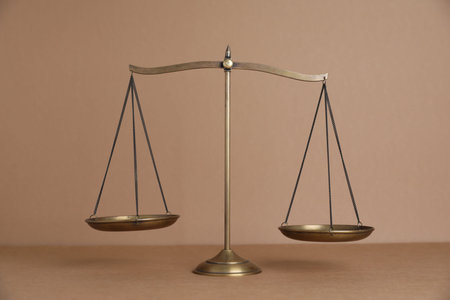 Golden scales of justice on light brown background