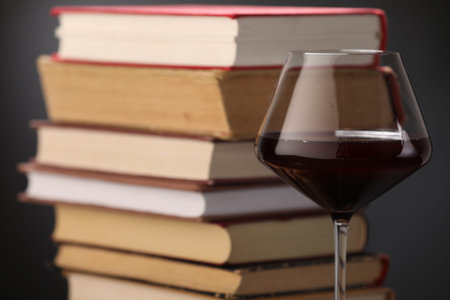 Red wine in glass and stack of books on dark background, closeupの写真素材