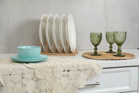 Drying rack with plates, bowl and glasses on countertop in kitchen