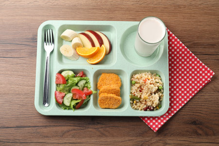 Plastic tray with tasty food, milk and fork on wooden table, top view. School lunch