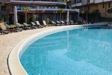 Outdoor swimming pool and sunbeds near hotel at luxury resort