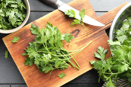 Fresh aromatic parsley and knife on black wooden table, flat lay
