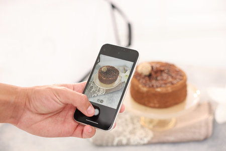 Man taking picture of chocolate cake in studio, selective focus. Professional food photography
