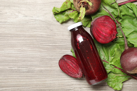 Superfood. Tasty juice in bottle and beetroots on light wooden table, flat lay. Space for textの写真素材