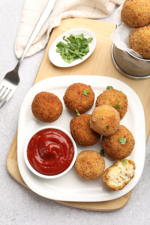 Delicious fried croquette balls with parsley and ketchup served on gray textured table, flat lay
