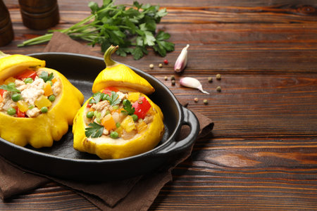 Tasty stuffed pattypan squashes in baking dish on wooden table, closeup. Space for text