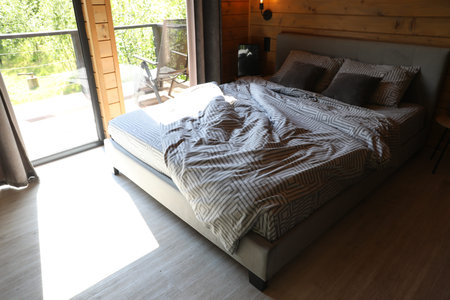 Comfortable bed near window in hotel room
