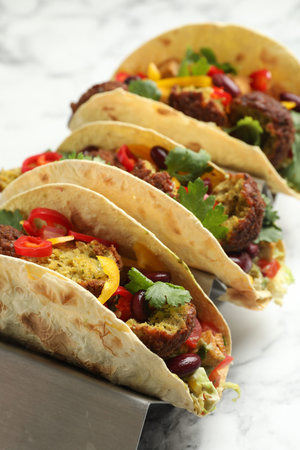 Tasty vegetarian tacos with falafel, tofu, beans and vegetables on white marble table, closeupの写真素材