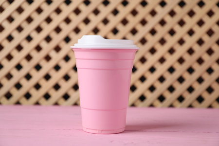 Disposable plastic cup on pink wooden tableの写真素材