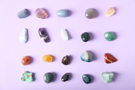 Aura. Different natural mineral stones on violet background, flat lay