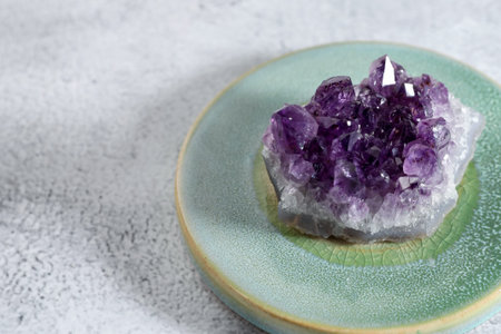 Beautiful amethyst on white textured table, closeup. Space for text