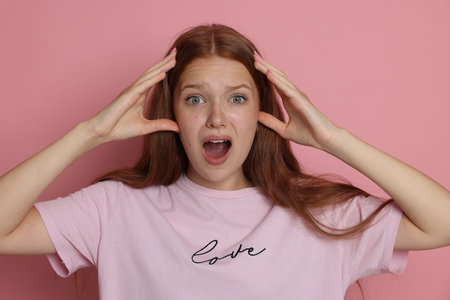 Teenage girl suffering from panic attack on pink background