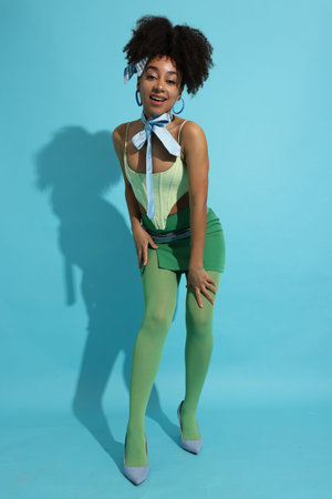 Fashionable portrait of beautiful Brazilian woman in stylish outfit on light blue backgroundの写真素材