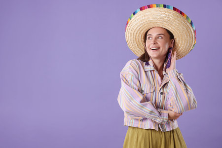 Smiling woman in sombrero hat on violet background. Space for text