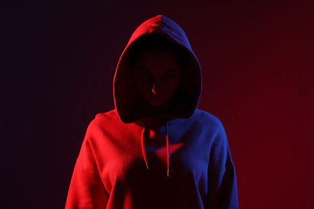 Anonymity. Woman hiding her face on dark red background