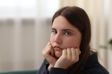Sad young woman at home, space for text