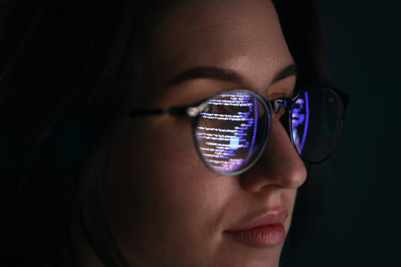 Young woman wearing glasses with reflection on dark background, closeup