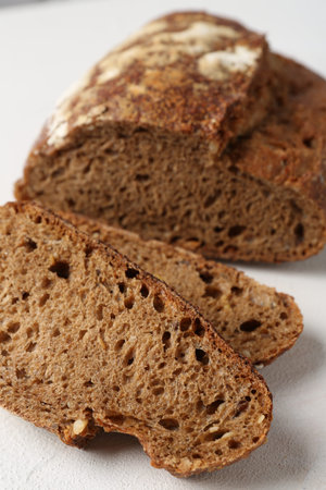 Pieces of fresh rye bread on white textured table, closeup