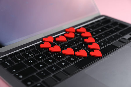Online dating site. Many red hearts on laptop, closeup