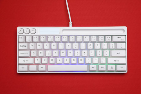 Modern white keyboard with RGB lighting on red background, top view