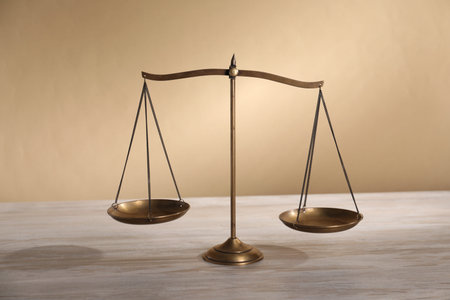 Scales of justice on table against beige background