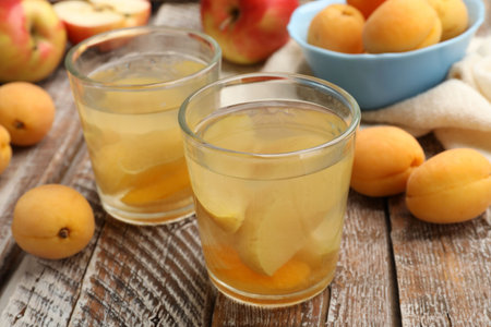 Tasty compot and fruits on wooden table, closeup