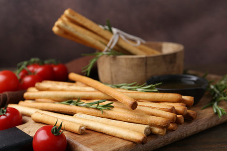 Delicious grissini sticks served on wooden table, closeup