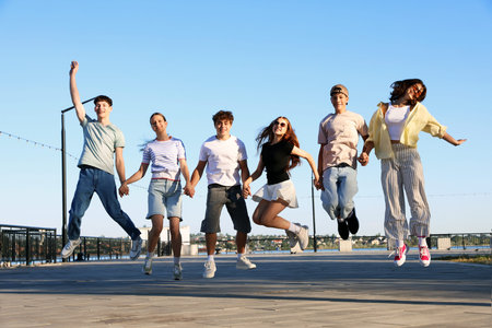 Group of happy teenage friends jumping outdoors on sunny morning