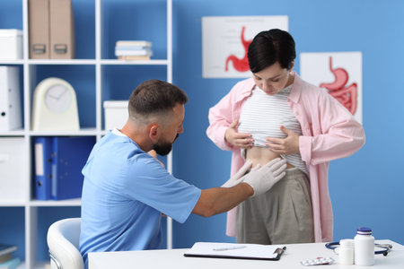 Gastroenterologist examining patient with stomach pain in clinic