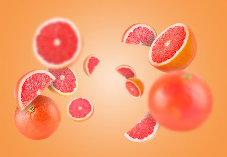Fresh grapefruits swirling in air against orange backgroundの写真素材