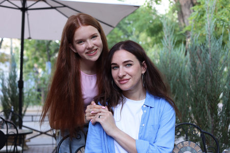 Portrait of beautiful mother and her teenage daughter in outdoor cafeの写真素材