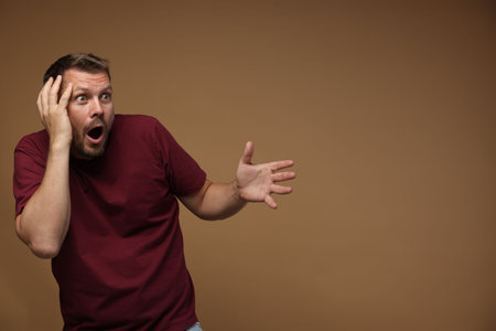 Man suffering from panic attack on brown background, space for text