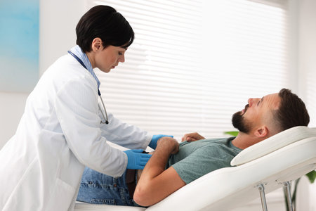 Gastroenterologist examining patient with stomach pain in clinic