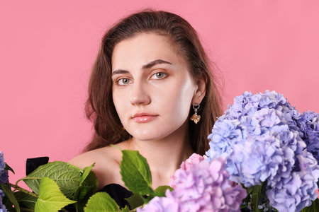 Portrait of beautiful woman with hortensia flowers on pink background