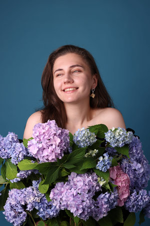 Smiling woman with hortensia flowers on blue background