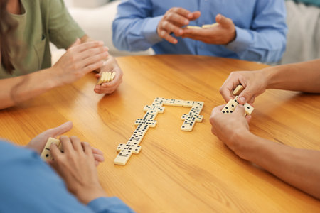 Friends playing dominoes at wooden table indoors, closeupの写真素材