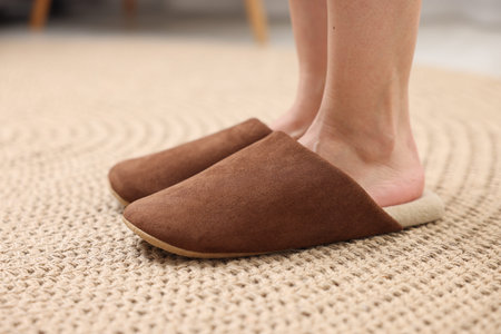 Woman in soft brown slippers on wicker mat, closeupの写真素材