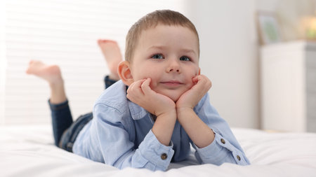 Smiling little boy on bed at home