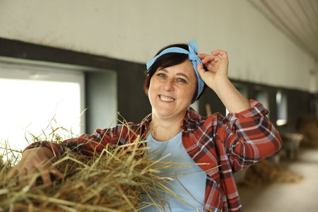 Portrait of farmer with hay in dairy farmの写真素材