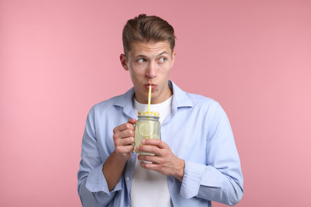 Man drinking lemonade from mason jar on pink background. Refreshing drinkの写真素材