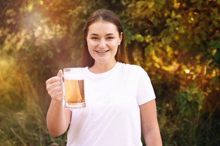 Young woman with glass of beer outdoorsの写真素材
