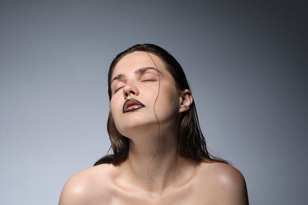 Young woman with black lip liner on light gray backgroundの写真素材