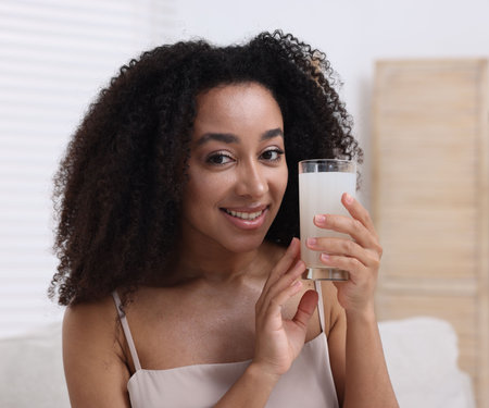 Beautiful Brazilian woman with glass of collagen water indoorsの写真素材