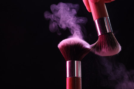 Makeup brushes with color eye shadow on black background, closeup.